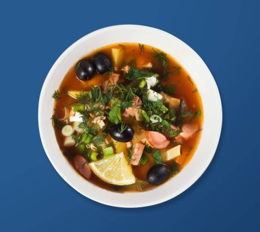 Beyaz bir tabakta Rus Solyanka çorbası. Yukarıdan bak. Hafif bir arkaplanda