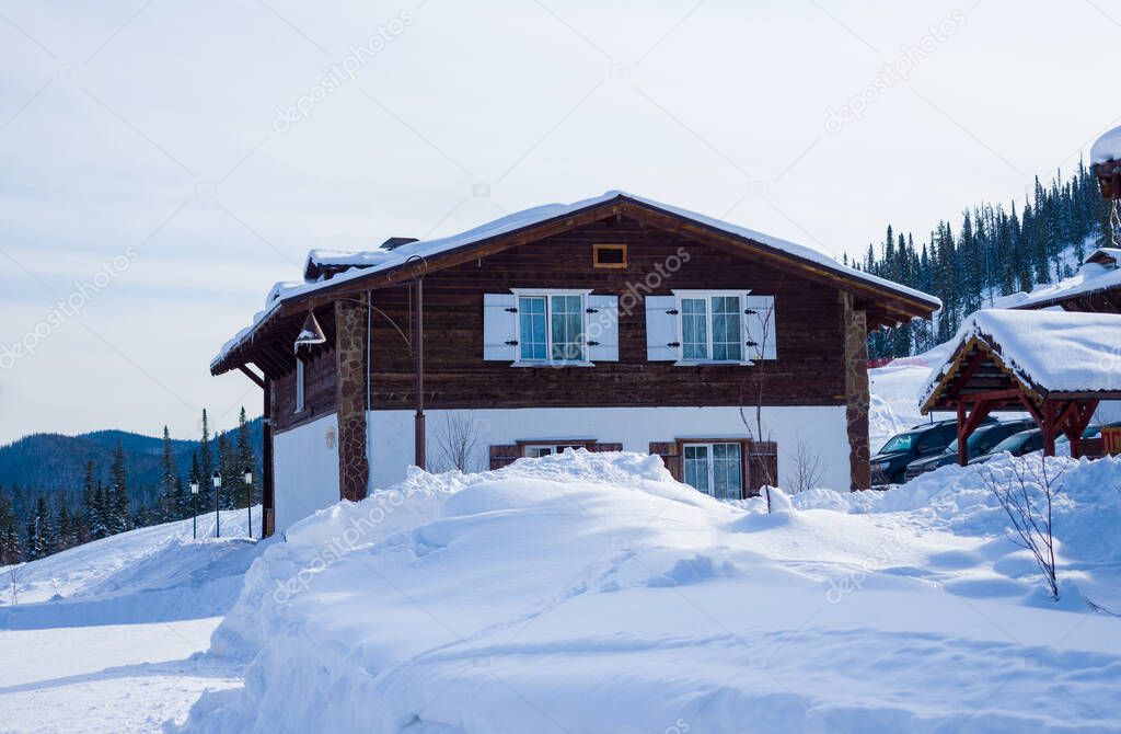 Wooden two-story Alpine-style house. Hotel in the ski resort Gornaya Salanga. Winter day