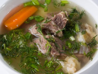 Shurpa çorbası. Beyaz bir kasede patates ve havuçlu et çorbası. Yakın plan.