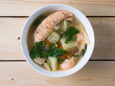 Beyaz kasede balık çorbası. Patates ve otlu somon. Üst görünüm