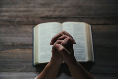 Eller inanç için kilise kavramı bir Kutsal Kitap üzerinde dua katlanmış