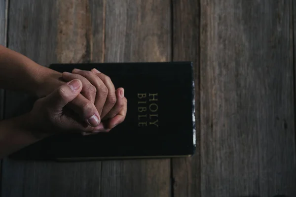 Handen gevouwen in gebed op een Heilige Bijbel in kerk concept voor geloof — Stockfoto