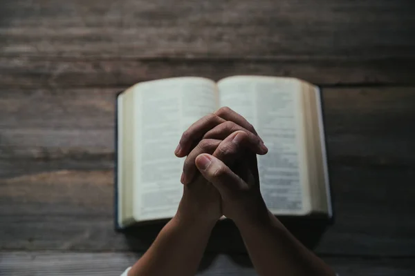 Mãos dobradas em oração em uma Bíblia Sagrada no conceito da igreja para a fé — Fotografia de Stock