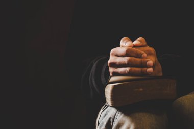 Soft focus on a hand of man while praying for christian religion