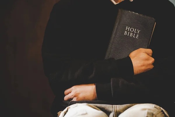 Nenucený muž se modlí s rukama spojenýma s Biblí svatou. — Stock fotografie