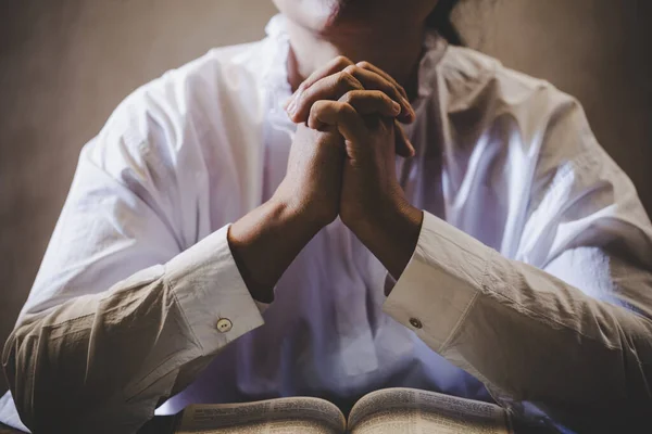 Mãos dobradas em oração em uma Bíblia Sagrada no conceito da igreja para fai — Fotografia de Stock