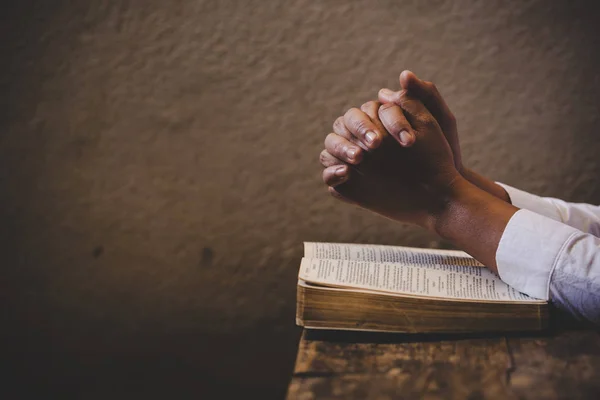 Hands folded in prayer on a Holy Bible in church concept for fai — 스톡 사진