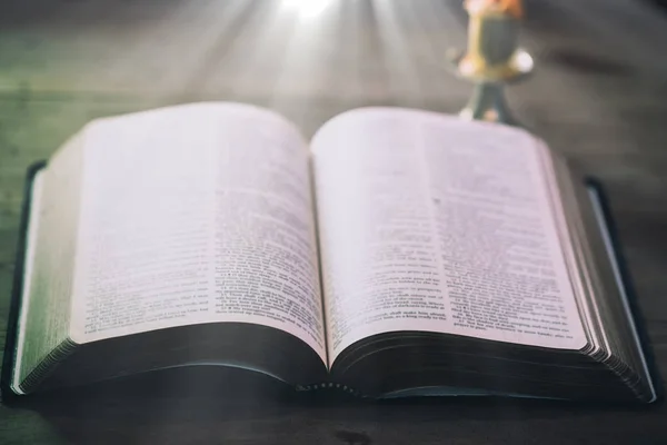 Livro aberto da Bíblia Sagrada na mesa de madeira contra a luz da janela . — Fotografia de Stock