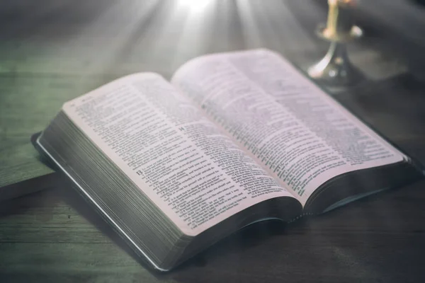 Pencerenin ışığına karşı ahşap masanın üzerinde açılmış kutsal kitap. — Stok fotoğraf