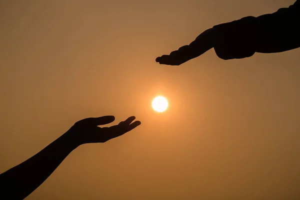 Giving a helping hand on the background of the sunset.