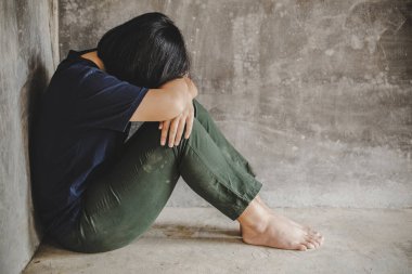 Yalnız, üzgün genç kız köşede ağlıyor ve dizlerini tutuyor. Depresyonda olan kadın odanın köşesinde oturuyor. Aile içi şiddet, taciz ve taciz kavramı