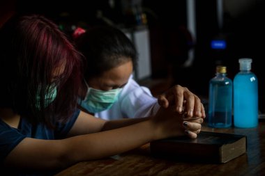 Tıbbi maske takan Asyalı bir aile, Coronavirus, Covid-19 adlı romandan etkilenen ve yakında iyileşmesi için dua eden insanlar için dua ediyor..