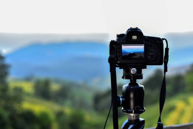 Art of Back Screen Dslr Camera, Dağın Üzerinde Mavi Gökyüzü Bulutuna Karşı Tripod 'un üzerinde duruyor. Teraslı Arkaplanda Yeşil Pirinç Tarlalarıyla Gün Işığı Günü.