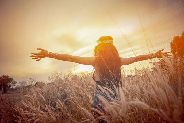 Çekici hippi kız yaşam tarzı. Tarlalarda kaygısız güzel bir kadın, yazın günbatımında açık havada mutlu bir şekilde elini uzatıyor. Çiçek tarlasında kulakları olan Bohem elbiseli güzel kızlar. Dans eden mutlu kadın gün ışığı.