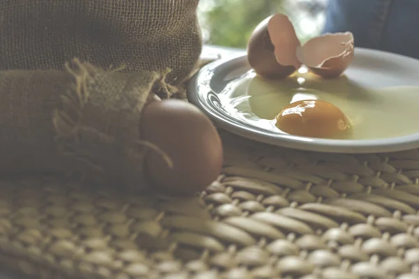 Fresh farm brown Chicken Egg.Separated egg white and yolk on a white plate over basketwork craft mat Water Hyacinth Pad.Food ingredient Egg yolk for baking cake,dessert or sweet.