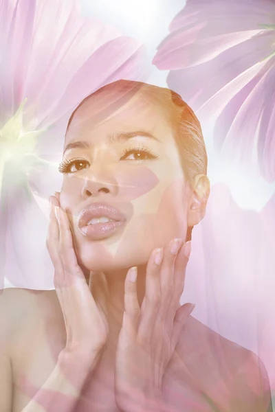 Double exposure of attractive woman face with clean fresh tan skin tone and pink flowers on white background. closeup portrait.