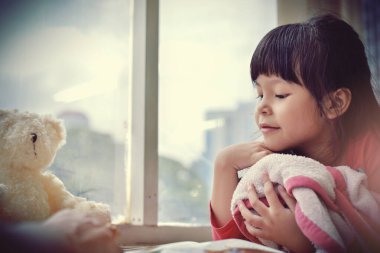 Şehir manzarasına karşı geniş pencereli annesiyle masal ödevi yapan ve öğrenen güzel bir kız. Ses tonunu süreç gibi ayır.