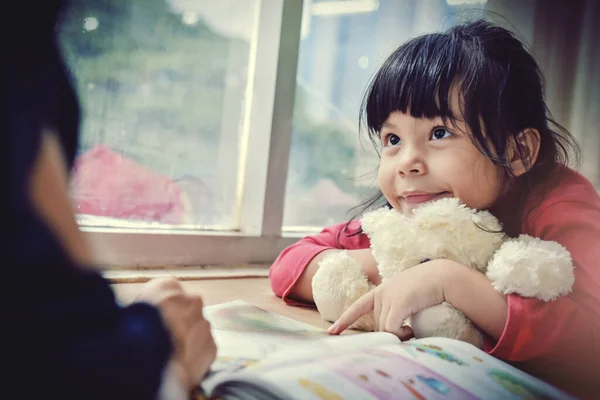 Şehir manzarasına karşı geniş pencereli annesiyle masal ödevi yapan ve öğrenen güzel bir kız. Ses tonunu süreç gibi ayır.