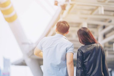 İş merkezi arka planında bavulu olan çift erkek gezginin arkası..