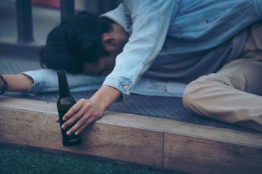 Partiden sonra. Sarhoş sakallı genç adam kaldırımda uzanıyor ve çok fazla bira içtikten sonra uyuyor..