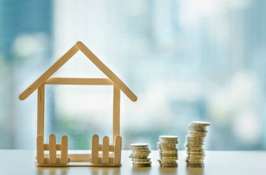 Bozuk para yığını bozuluyor. Mini ahşap ev ve bozuk para yığını düşüyor. İpotek ve gayrimenkul yatırımı veya Sigorta Finans ve Yatırım konsepti.