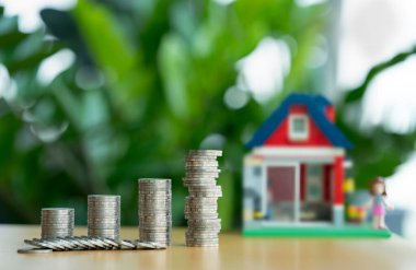 Bozuk para yığını bozuluyor. Mini ahşap ev ve bozuk para yığını düşüyor. İpotek ve gayrimenkul yatırımı veya Sigorta Finans ve Yatırım konsepti.