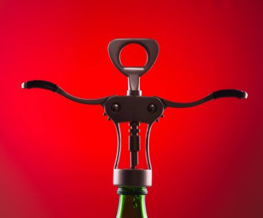 Şişenin boynundaki kırmızı arka planda şarap şişelerini açmak için tirbuşon.