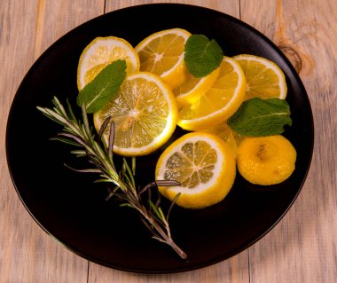 Siyah bir tabakta limon ve nane ve ahşap bir arka planda