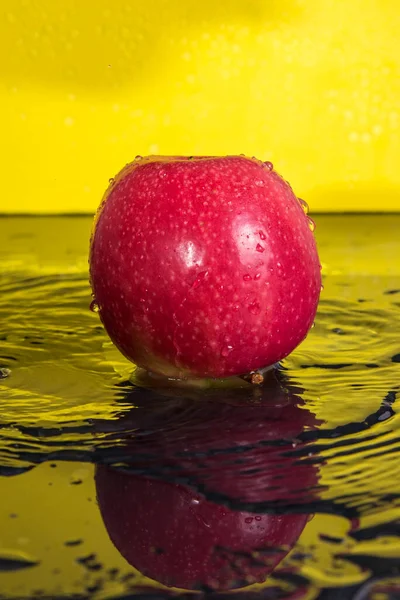 Rote Äpfel Mit Tropfen Wasserspritzer Auf Gelbem Hintergrund — Stockfoto