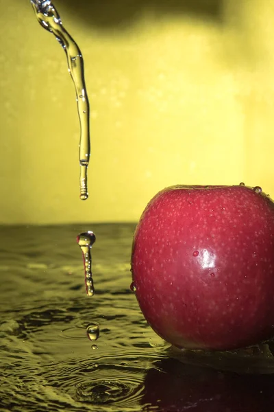 Rote Äpfel Mit Tropfen Wasserspritzer Auf Gelbem Hintergrund — Stockfoto