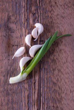 Yeşil soğan, ahşap arka planda sarımsak.