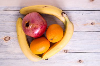  Portakallı nar, ahşap arka planda muzlar.