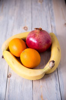  Portakallı nar, ahşap arka planda muzlar.