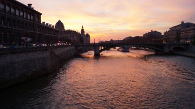 Paris 'te muhteşem bir gün batımı. Nehir ve binaların üzerindeki köprüye bakın. Fransa 