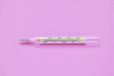 Beyaz lateks eldivenle elini kapat. Pembe arka planda cıva termometresi olsun. Sıcaklık termometrede 37.1 derece. Coronavirüs hastalığı, sağlık ve ilaç kavramı, virüs önleme