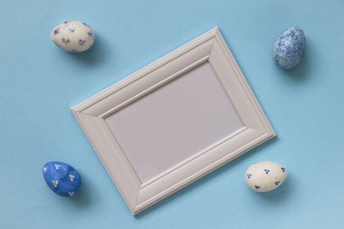 Mutlu Paskalyalar. Beyaz ve mavi benekli paskalya yumurtaları ile beyaz çerçeve mavi arkaplan üzerine metin için kopyalama alanı