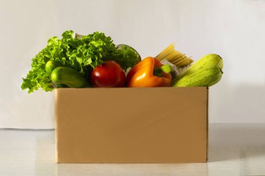 Yemek servisi. Yemek bağışı masada. Muhtelif konserve yiyecekler, tahıllar, makarna ve sebzeler ile karton kutuya yardım et. Gönüllü kutusu.