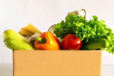 Yemek servisi. Yemek bağışı masada. Muhtelif konserve yiyecekler, tahıllar, makarna ve sebzeler ile karton kutuya yardım et. Gönüllü kutusu.