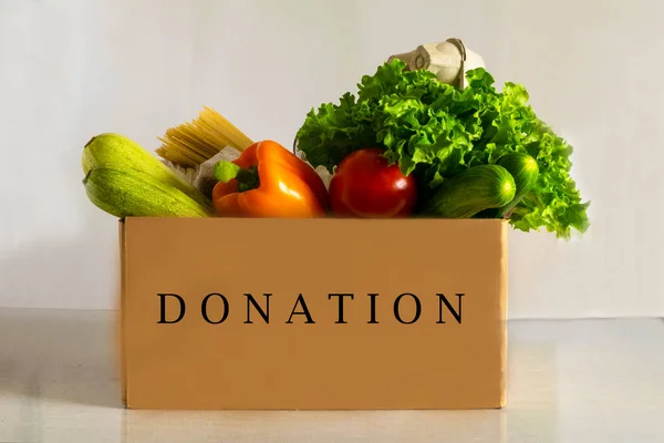 Food delivery. Food donation on table. Help cardboard box wiht various canned food, cereals, pasta and vegetables. Volunteer box.