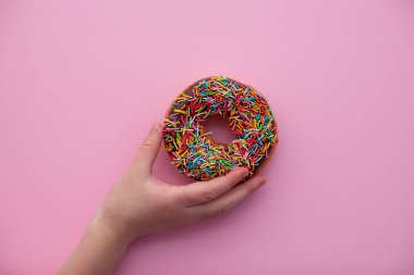 Elinde pembe arka planda çikolatalı çörek.. 