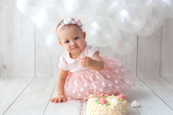 First baby birthday. Balloon garland on background. Disgruntled kid