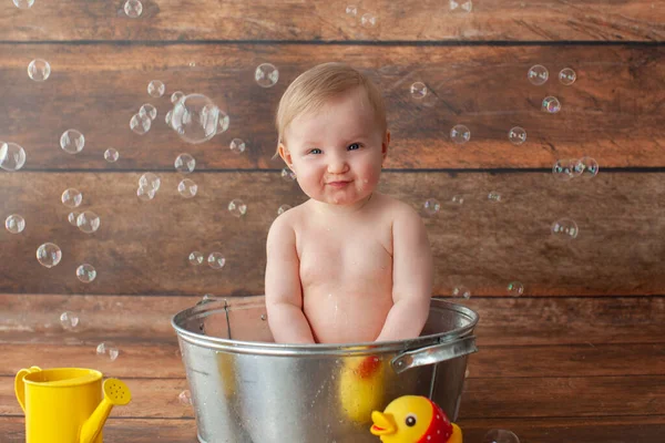 Kleines Baby nimmt ein Bad. Gummienten und eine gelbe Gießkanne. — Stockfoto