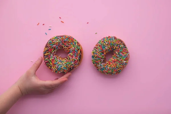 Donut de chocolate sobre fondo rosa con mano . —  Fotos de Stock