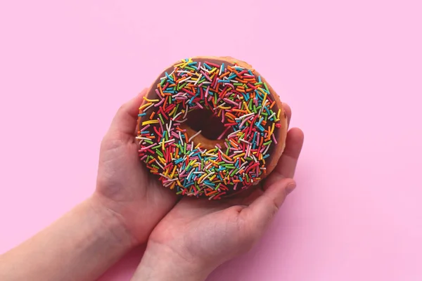 Chocolate donut on pink background in hand. — Stock Photo, Image