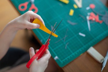 Yedi yaşında bir kız, makas sarısı kağıdıyla kesiyor..