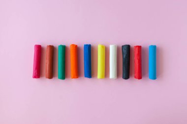 Pembe arka planda çok renkli çocuk plastikçesi.