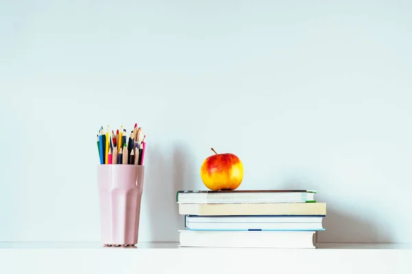 Stack of books, apple and multicolored pencils. Back to school education concept