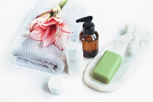 Cosmetics, skin tonic, towel and handmade soap on white table. Spa treatments and skin care concept.