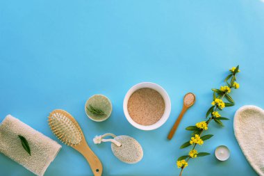 Doğal kozmetik ürünleri, sabun, himalaya tuzu, kozmetik eldivenler, sünger taşı, tarak, mavi bir masada havlu. Sıfır atık, plastiksiz. Sürdürülebilir yaşam tarzı konsepti. Üst görünüm, düz görünüm, kopyalama alanı.