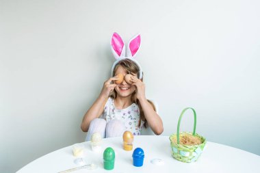 Tavşan kulaklı şirin bir kız Paskalya yumurtalarıyla oynuyor.